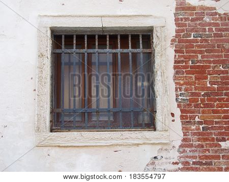 window with bars in an old distressed white and brick wall