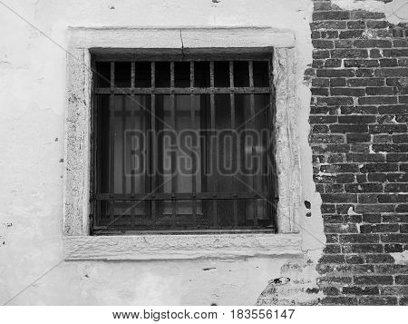 Old barred window on a distressed brick wall