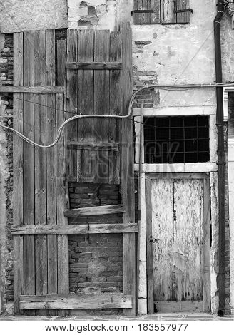 Old board up whouse with weatherd grey planks brick walls and a white door