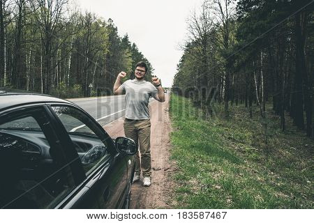 yang man stratching near car after long road on road aside