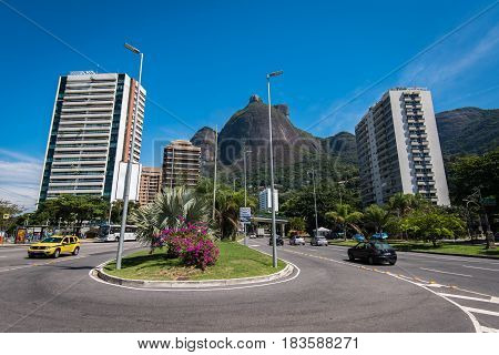 Rio de Janeiro, Brazil - April 6, 2017: Main avenue crossing Sao Conrado has apartment buildings built along it, and is surrounded by mountains.