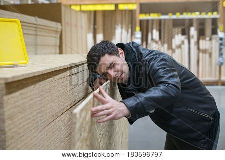 male customer choosing flakeboard or Oriented strand board OSB in the supermarket. Buying Construction and building material. Man is measuring flakeboard.