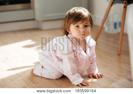 Crawling baby girl wearing pajams on kitchen floor