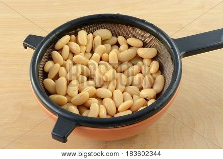 Rinsed canned Cannellini white kidney beans draining in strainer to reduce salt