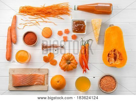 Orange set of objects, pumpkin and carrots, juice, salmon, cheese and pepper, topview