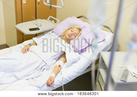 Bedridden female patient lying in hospital bed, recovering after surgery.