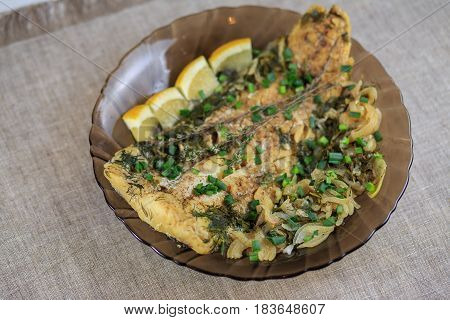 Fillet Of The Baked Fish In Seasonings And Greens On A Black Plate