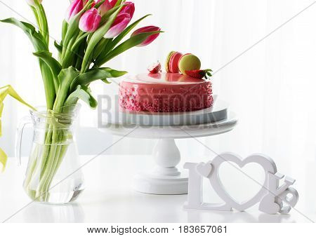 Pink romantic cake decorated with macaroons and strawberry. Delicious creamy cake with strawberies and macaroons on table closeup