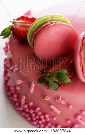 Pink romantic cake decorated with macaroons and strawberry. Delicious creamy cake with strawberies and macaroons on table closeup
