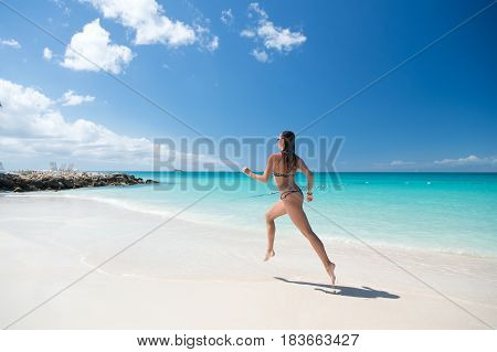 woman runing with beautiful body in swimsuit running in ocean water sunny day at tropicl beach sport and wellness concept