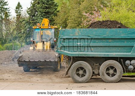 The tractor loaded the earth into the lorry. Ternopil. Repair of the park. Land works. 04 27 2017