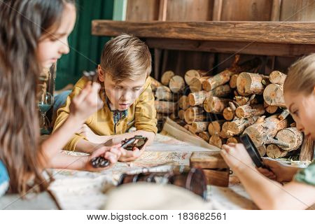 Focused Little Travelers Looking At Map Together On Porch
