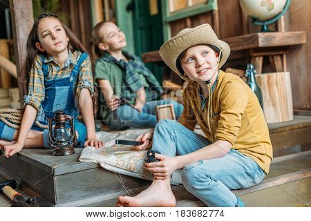 Adorable Little Kids Travelers Sitting Together With Map On Porch