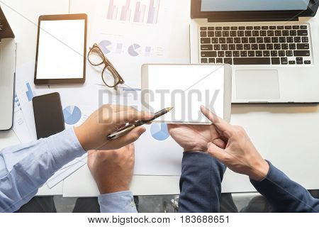 Image of two young businessmen working with laptop tablet smartphone and financial document data graph on table in office.