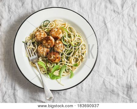 Spaghetti with cheesy chicken meatballs and zucchini noodles. Delicious lunch on a light background top view