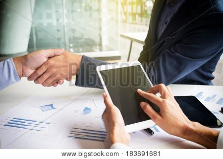 Teamwork concept of office working Young business men shaking hands with document graph background.