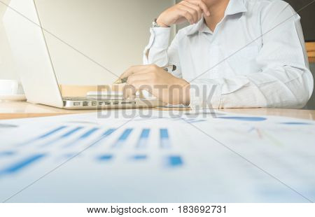 Business man working at office with laptop and documents on his desk Financial graph data.