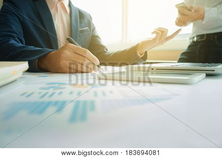 Business team two colleagues discussing new plan financial graph data on office table with laptop and digital tablet.
