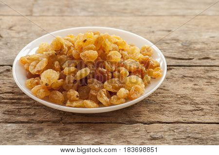 dried grapes close up on white plate on wooden background