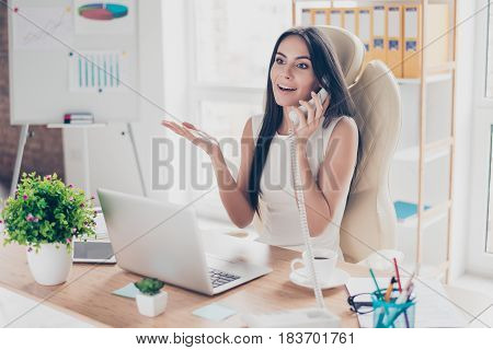 Excited Surprised Young Business Lady Is Talking On The Phone At Her Workplace. She Is Wearing White