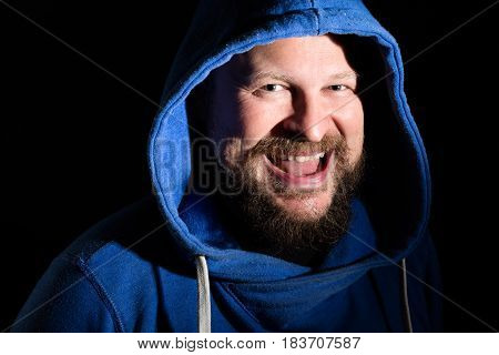 Solid bearded middle-aged man in a hood emotional portrait on black background