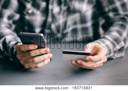 A man uses a mobile phone to pay for tariffs and services purchased on the Internet
