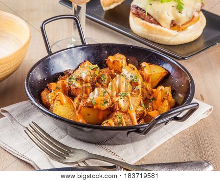 Patatas bravas spicy potatoes a typical Spanish dish with fried potato cubes and a spicy garlic sauce.