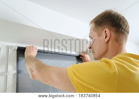 Man is holding fabric window blind gray.