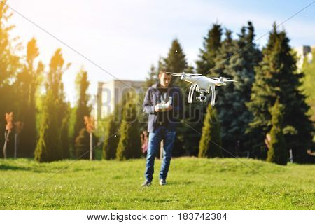 Man controls a quadrocopter. Selective focus on drone men is blurred. Launching a quadrocopter in the park