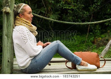 Beautiful young blond contemplative woman in a sitting enjoying nature