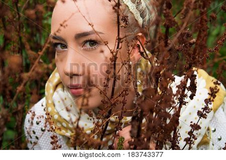 Close up shot of beautiful young latin girl behind some forest weeds