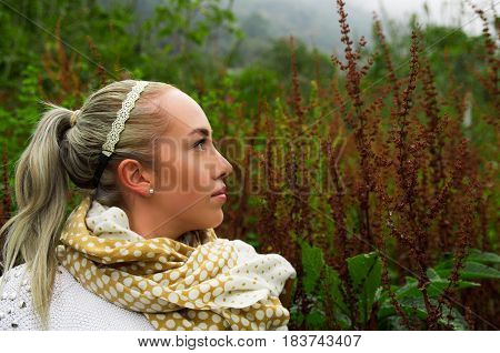 Pretty young reflective woman standing looking up in a mountain