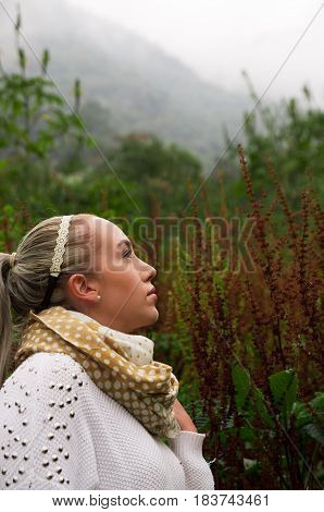 Pretty young reflective woman standing looking up in a mountain