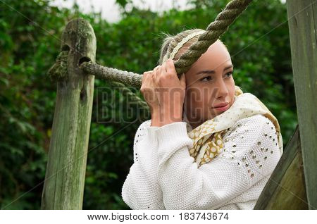 Attractive young latin woman in a forest walking bridge looking relfective