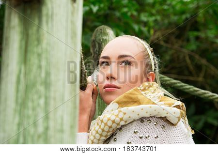 Close up shot if young blond girl sitting in a walking wooden bridge looking peaceful