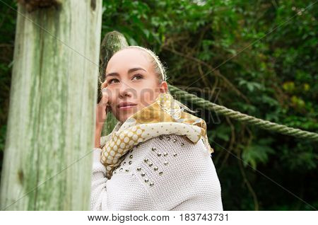 Close up shot if young blond girl sitting in a walking wooden bridge looking peaceful