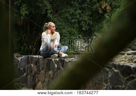 Attractive young woman sitting in a cold forest by the river enjoying the view