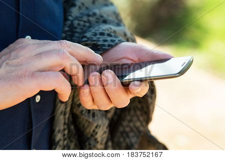Mock up of a man holding and using device and touching screen outdoor. Smartphone in male hands closep.