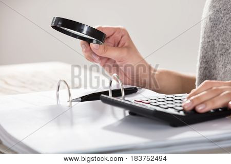 Close-up Of A Businesswoman Examining The Documents With Magnifying Glass
