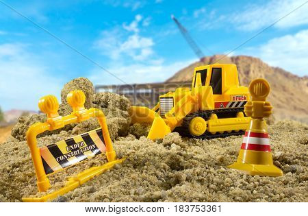 Bulldozer toy standing on a construction ground on a sunny day with warning signs and fence. Background used from Pixabay under cc0 license.