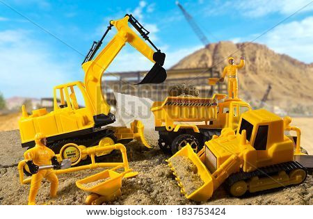 Excavator, construction truck, bulldozer & worker toys standing on a construction ground on a sunny day. Background used from Pixabay under cc0 license.
