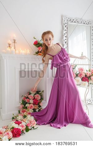 Lovely girl in beautiful dress posing in studio. Spring flowers and a romantic mood.