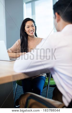 Smiling businesswoman sitting with male colleague at table in office