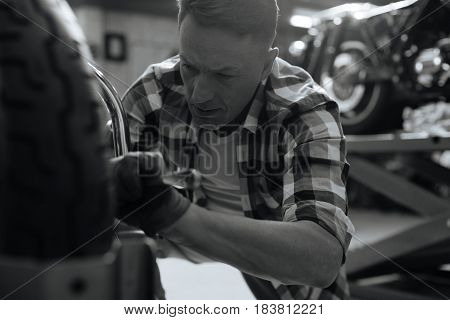 Do it right. Accomplished gifted precise man fixing some problems while repairing a bike and fulfilling his job in repair shop