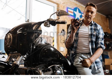 Ready for a run. Respectable virile mature mechanic showing that the bike being in perfect condition after he repairing it for some time