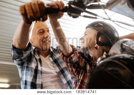 We gonna ride it soon. Charming hilarious nice father entertaining his child by giving her a tour around his workshop and sitting her on his bike