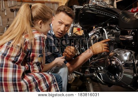 Being a great teacher. Talented adorable handsome dad making sure his daughter understanding what he saying and pointing at the details on the bike