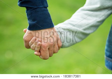 Hands. Father's and his son hands. Dad leading son over summer nature outdoor. Male and children hands closep. Family, trust, protecting, care, parenting concept.