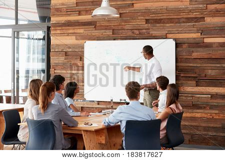 Young black man at whiteboard giving a business presentation