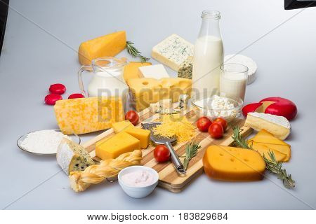 Cheeses, Cherry Tomatoes and Milk on the Wooden Platter - on the Grey Background